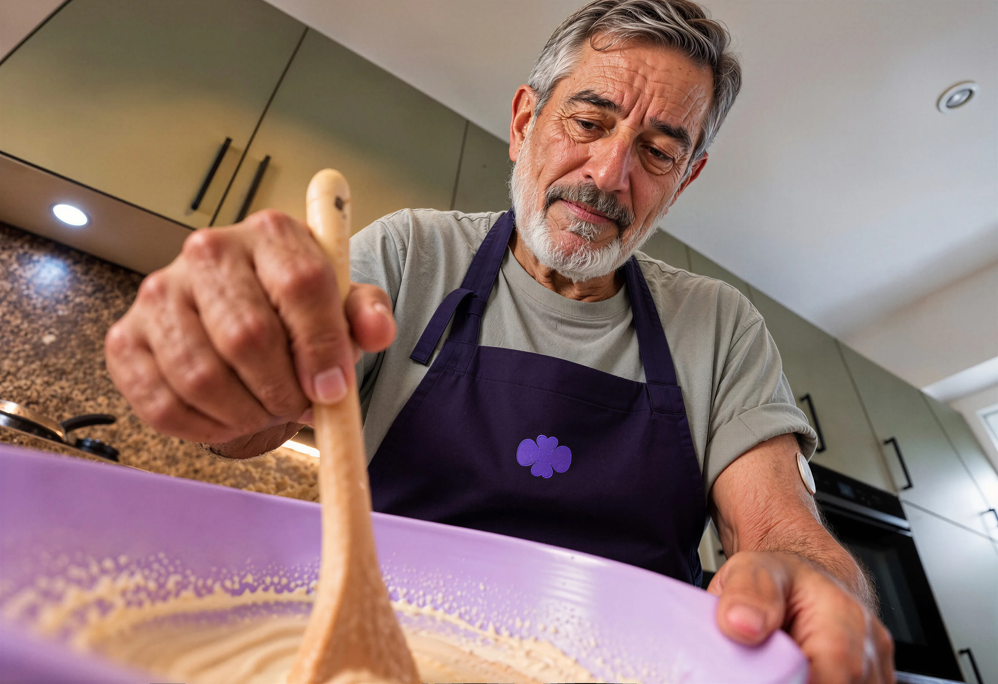 Ein Mann mit Schürze rührt mit einem Holzlöffel in einer Schüssel.
